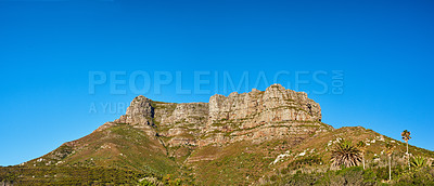 Buy stock photo Landscape of a mountain peak in Cape Town, South Africa. Rugged mountaintop with green shrubs, grass, trees and a blue sky. A popular tourist attraction and adventure hiking trail near table mountain