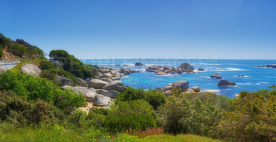 Buy stock photo Landscape of many rocks in the ocean surrounded by green bushes or shrubs. Large stones around tidal pool in the sea. Boulders of various shapes in blue water near coastal area in Hout Bay, Cape Town