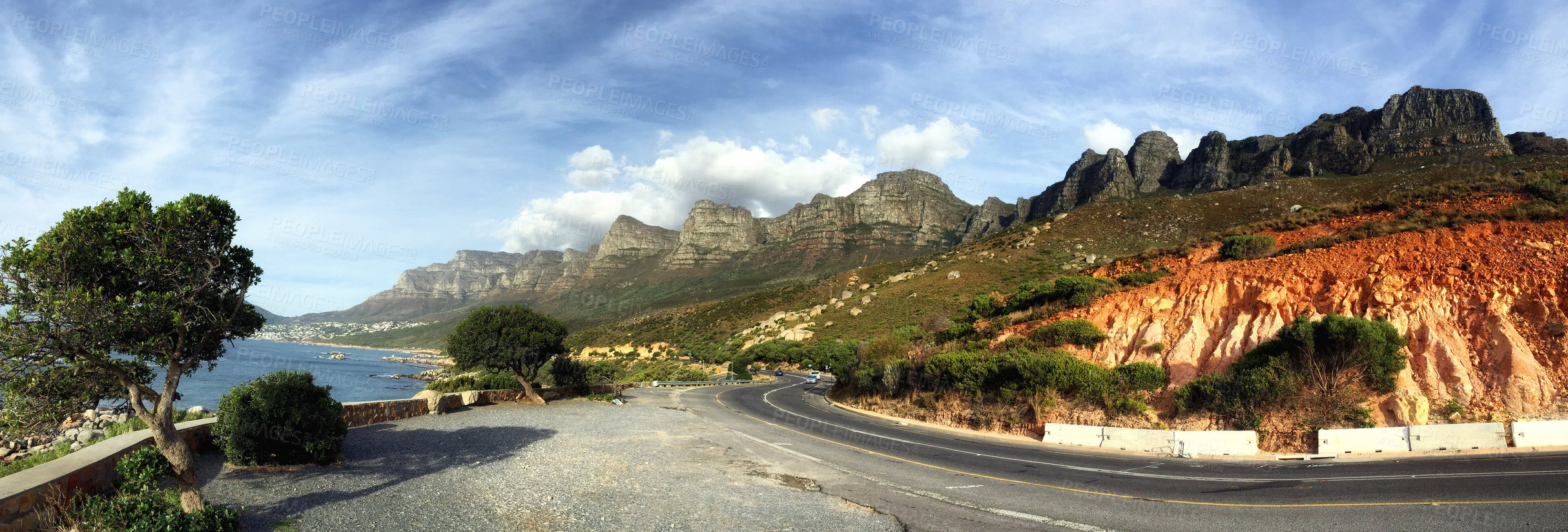 Buy stock photo Quiet mountain road beside the coastline in South Africa. Panorama view of an empty mountain pass near the sea in Cape Town. Scenic drive through the countryside in nature against a blue cloudy sky.