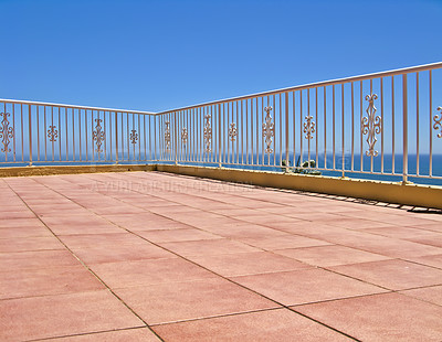 Buy stock photo Beach house balcony or terrace with tiled floor and white fence. Summer view with a classic barricade overlooking the sea or ocean with a blue sky background. Seascape scenic view at a holiday lodge