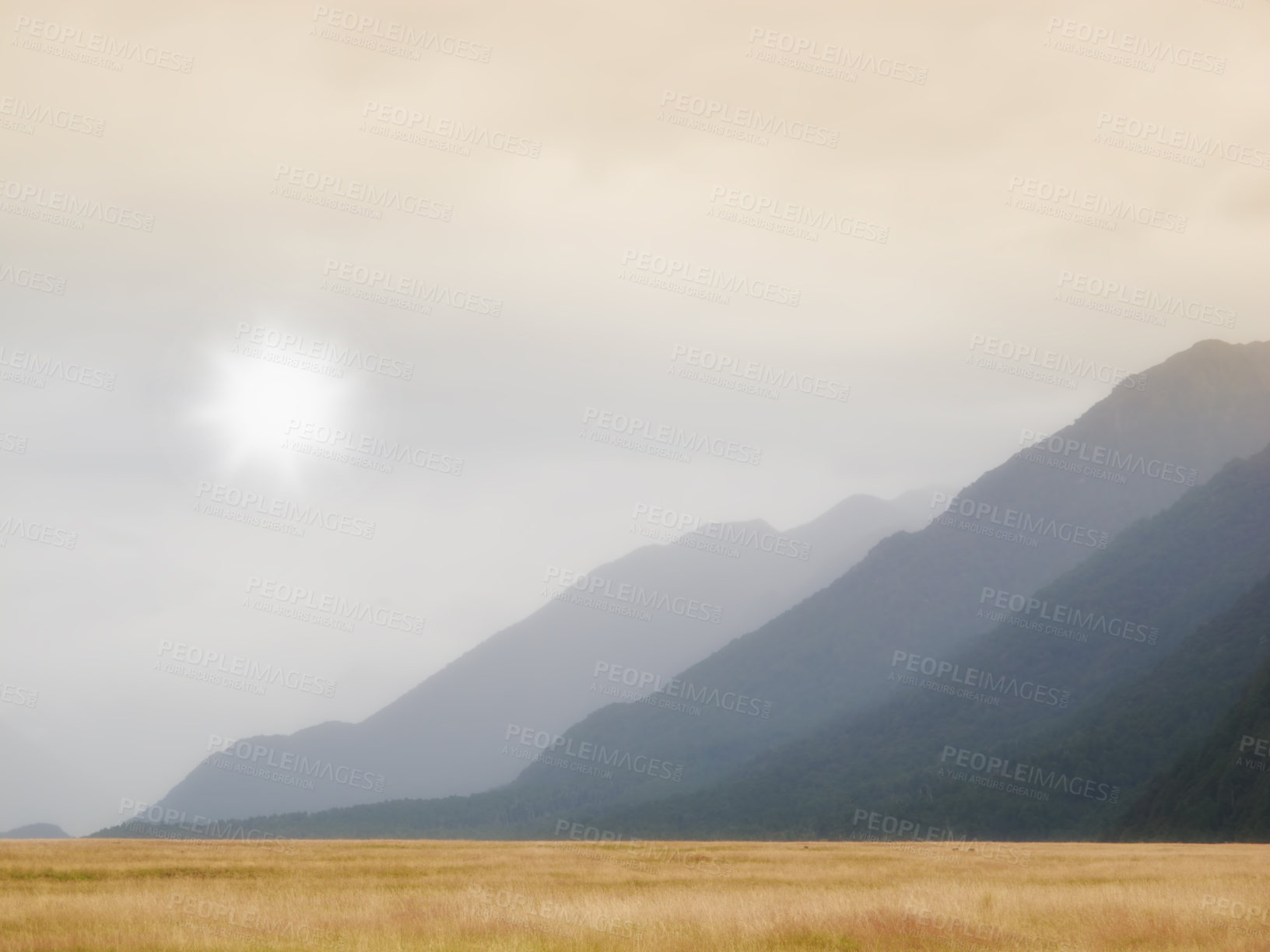 Buy stock photo Scenic view landscape of dry grassland or meadow with mountains or hills in the background with copyspace. Scenery of mother nature, sun shining and overcast cloudscape in the early morning