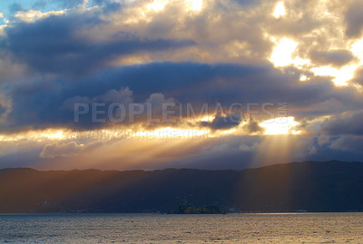 Buy stock photo Sun light breaking through dark cloudy copyspace over a calm ocean. Sunlight shining through thick clouds in the early morning. Rays of light making a breakthrough, through heavy, suffocating clouds 