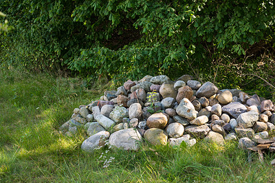 Buy stock photo Stacked large stones or rocks on a field of green grass. Rocks along a remote hiking trail in nature. Collected pile of stones marking forest ground, symbolising a small grave on a hiking trail 