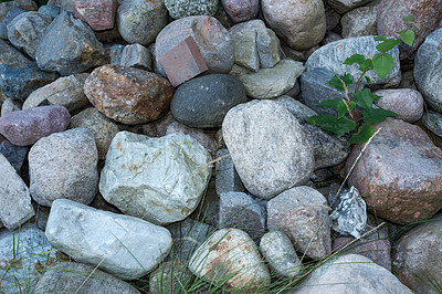 Buy stock photo Zoomed pile of large stones or rocks with green plants growing between. Above view of rocky landscape along a remote hiking trail in nature. Scenic rough terrain. Textured background or wallpaper