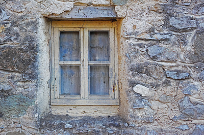 Buy stock photo Closeup of a wooden window in a stone wall of an old grey house. Boarded up square window frame in a historic rustic building. Architecture and background of a rural structure outside with copyspace