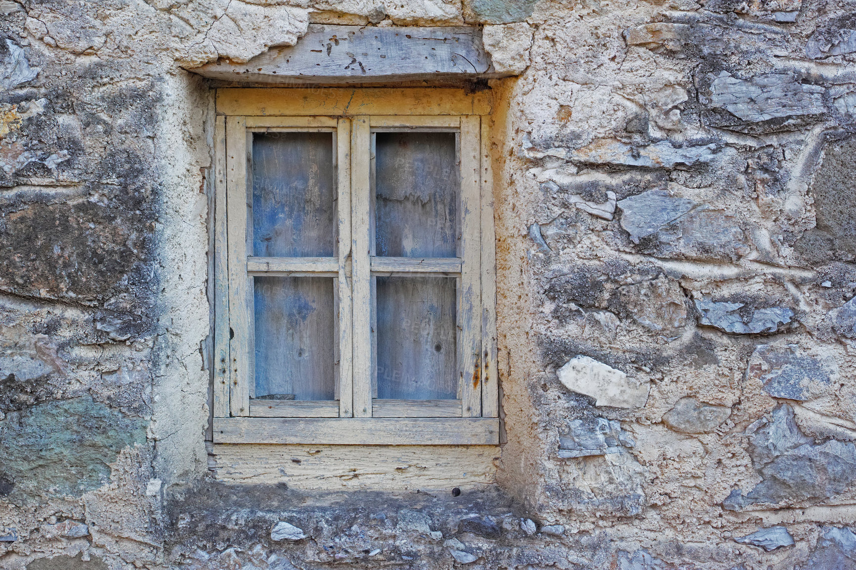 Buy stock photo Closeup of a wooden window in a stone wall of an old grey house. Boarded up square window frame in a historic rustic building. Architecture and background of a rural structure outside with copyspace