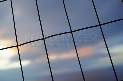 Buy stock photo Iron fence in vertical, horizontal lines against a blur sky background. Wire meshed in rectangle shapes for security or safety concept. The texture of window patterns or dark silhouettes of a gate