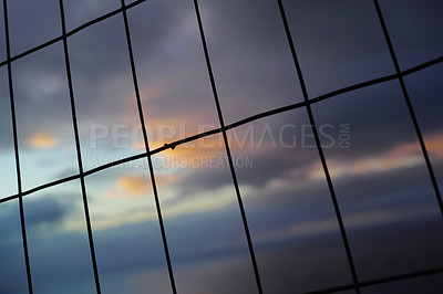 Buy stock photo Closeup of a wire fence at sunset. Background of vertical and horizontal lines. Silhouette of wire mesh in rectangle shapes for security concept. 