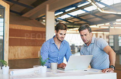 Buy stock photo Shot of two colleagues working together on a laptop while sitting in an office