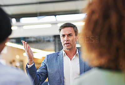 Buy stock photo Shot of a serious looking manager talking to his staff in an office