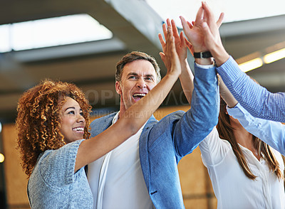 Buy stock photo Shot of a group of smiling colleagues high fiving together in an office