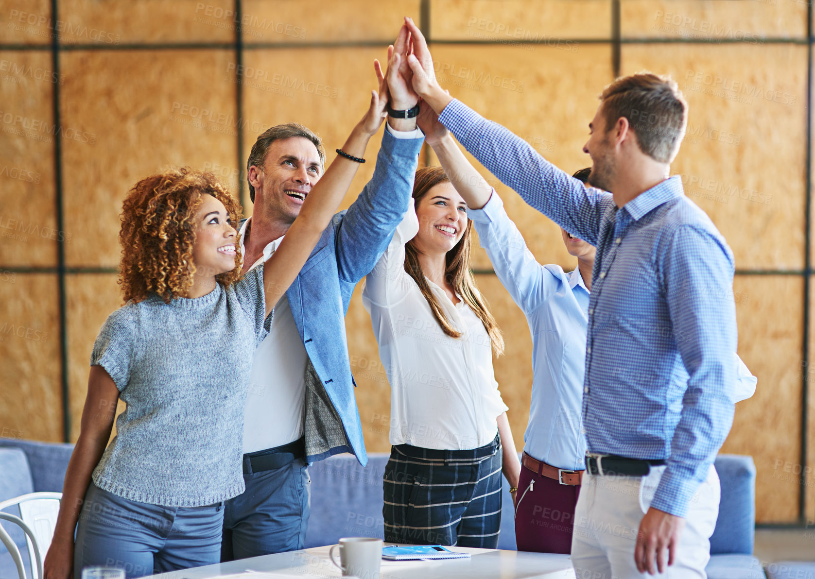 Buy stock photo Shot of a group of smiling colleagues high fiving together in an office