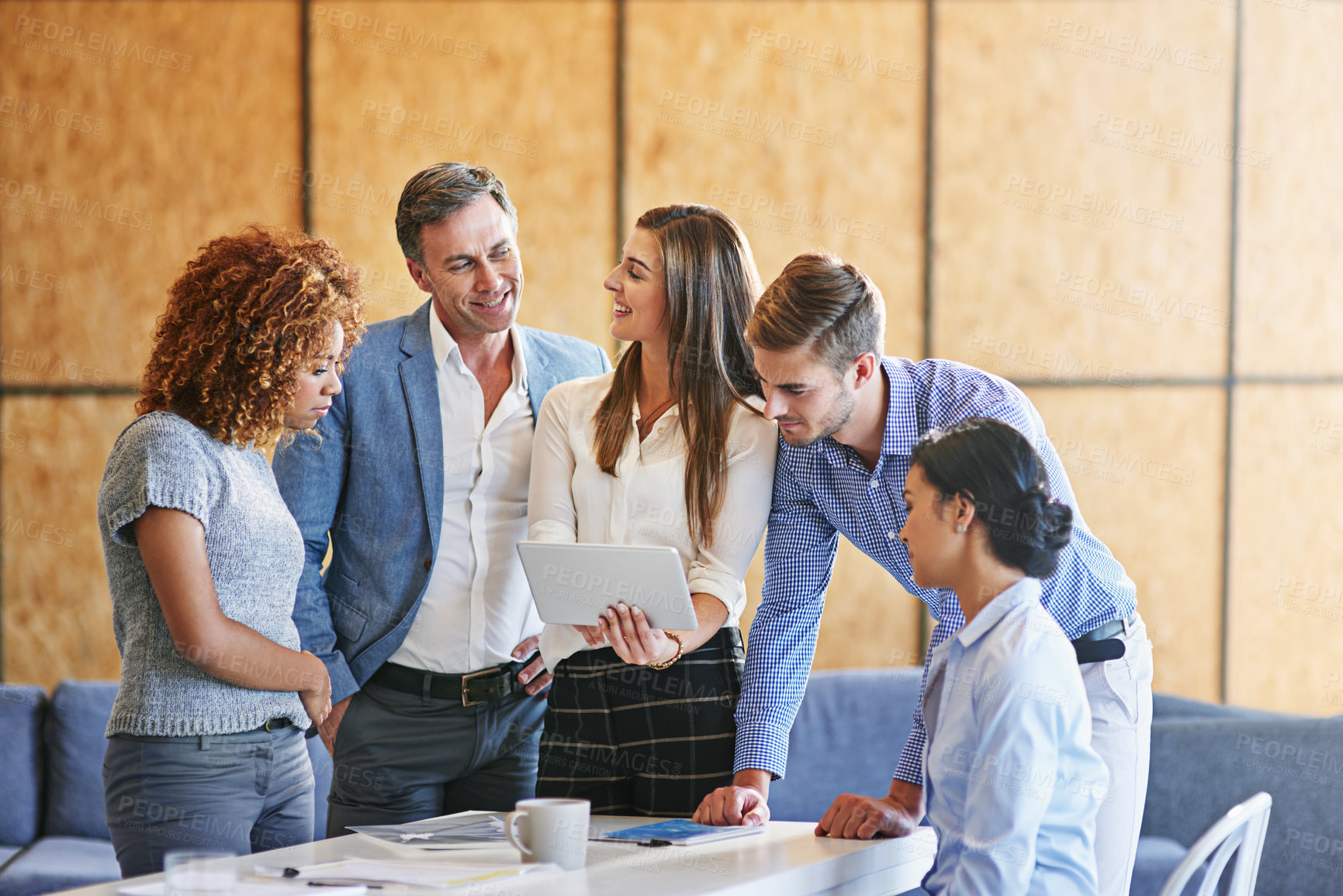 Buy stock photo Shot of a group of colleagues working together on a digital tablet in an office