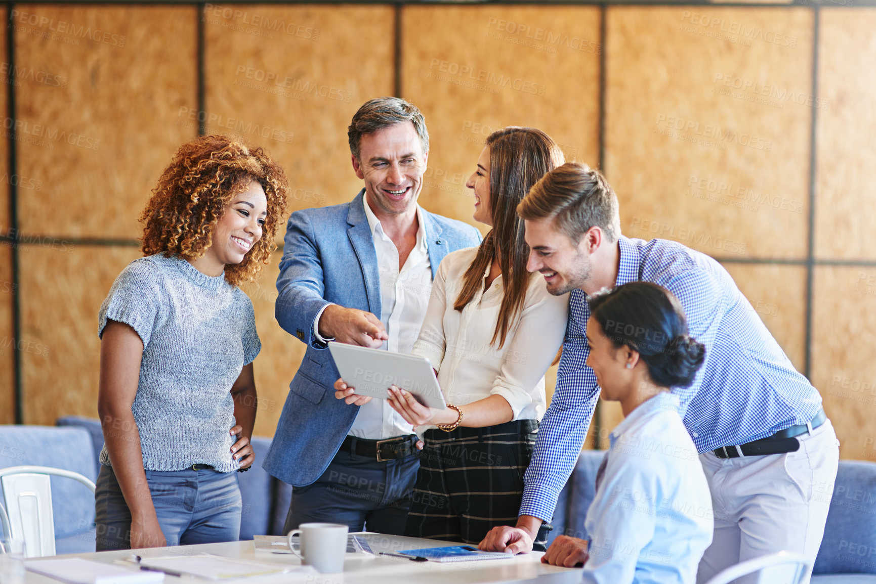 Buy stock photo Shot of a group of colleagues working together on a digital tablet in an office