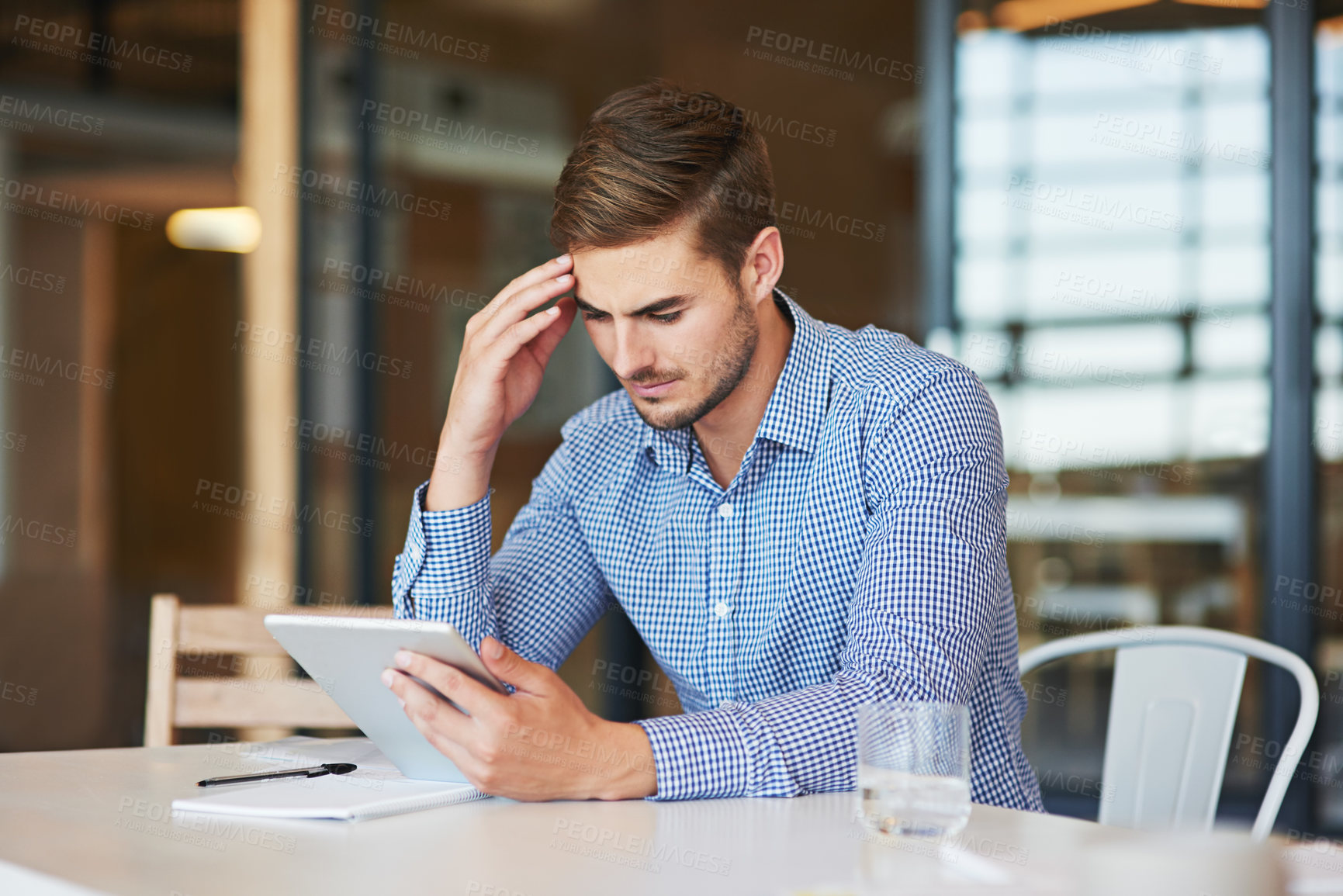 Buy stock photo Shot of a young businessman using a digital tablet in an office