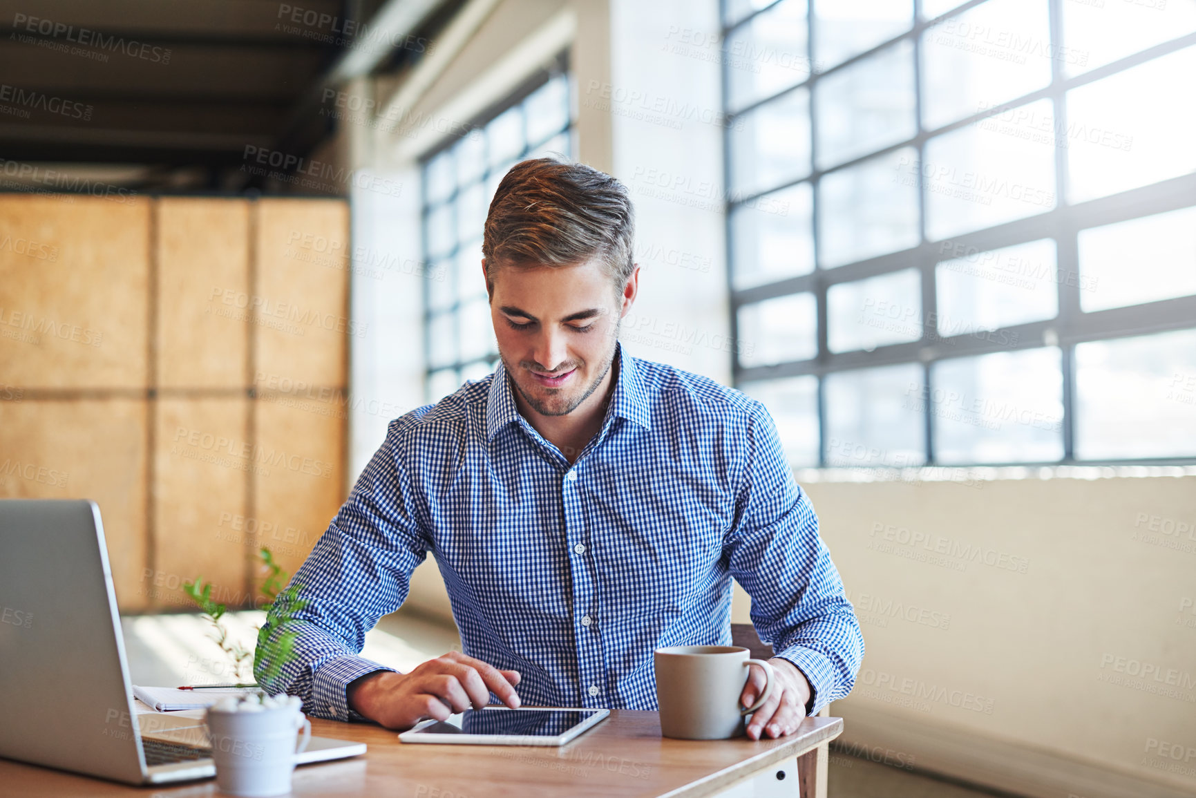 Buy stock photo Shot of a young businessman using a digital tablet in an office