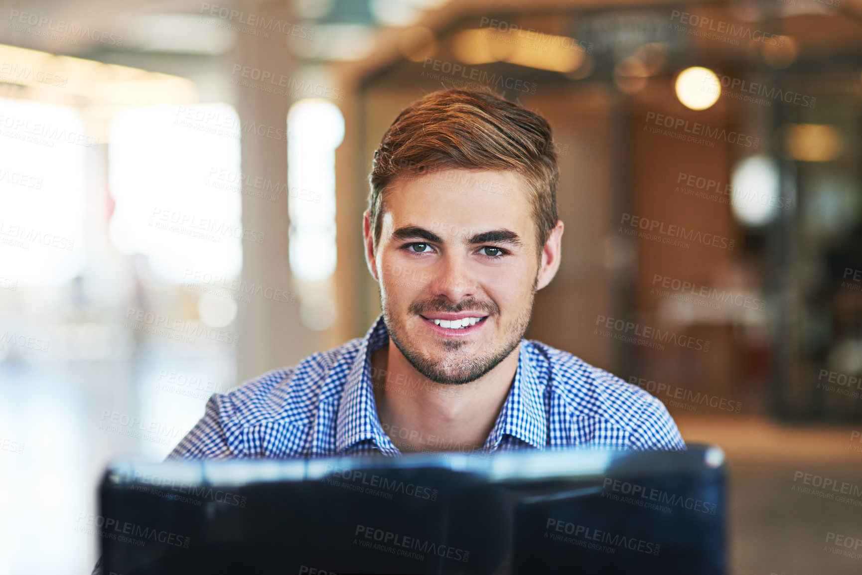 Buy stock photo Shot of a young businessman using a computer in an office