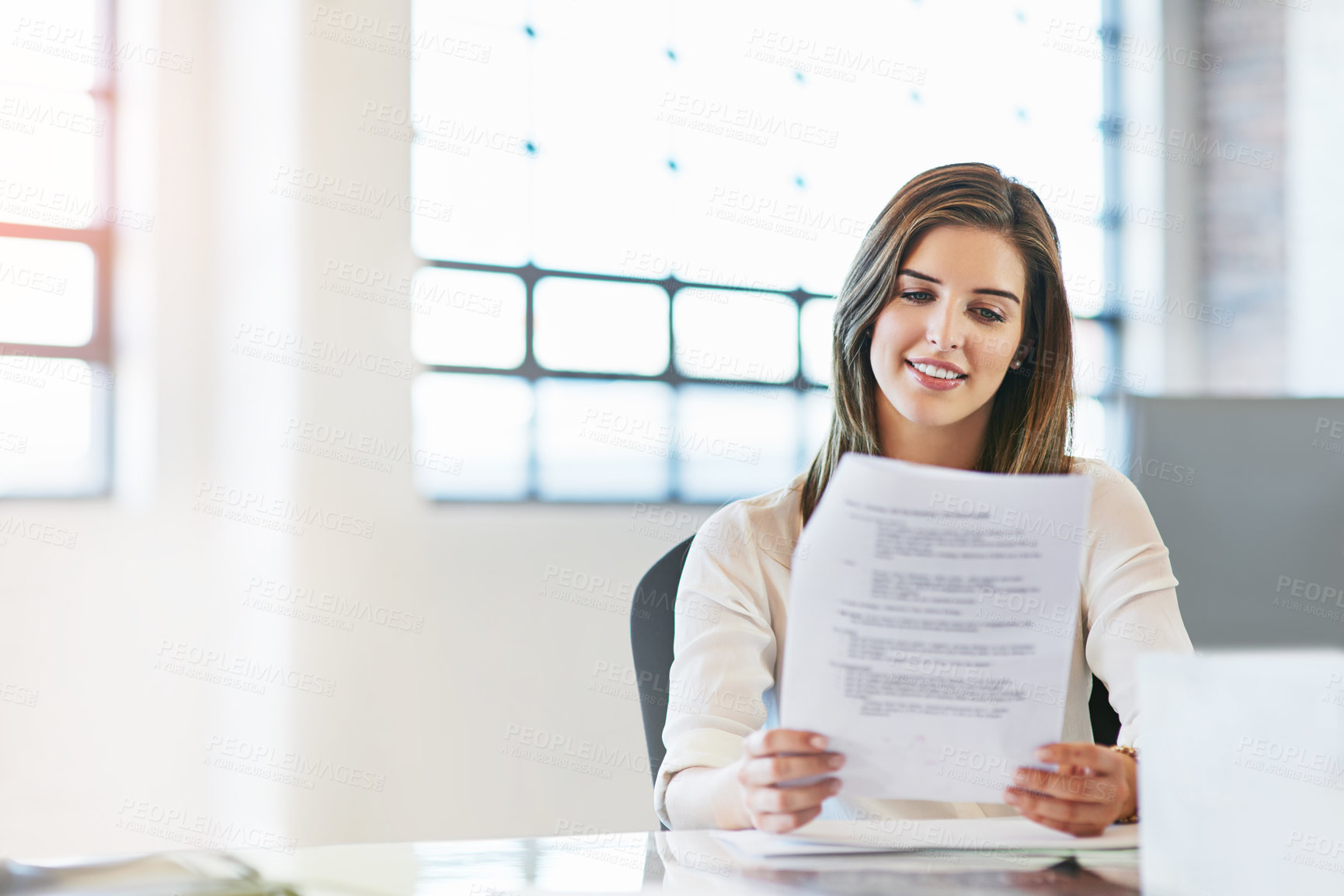 Buy stock photo Shot of a young businesswoman reading a document in an office