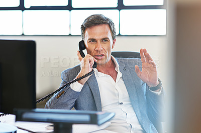 Buy stock photo Shot of a mature businessman making a serious call on the phone at work