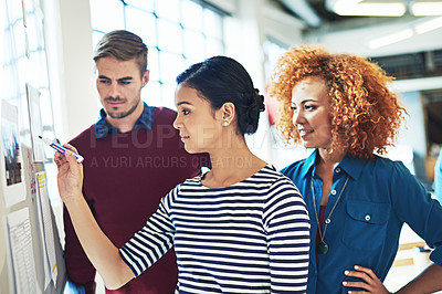Buy stock photo Shot of designers brainstorming on a whiteboard in an office