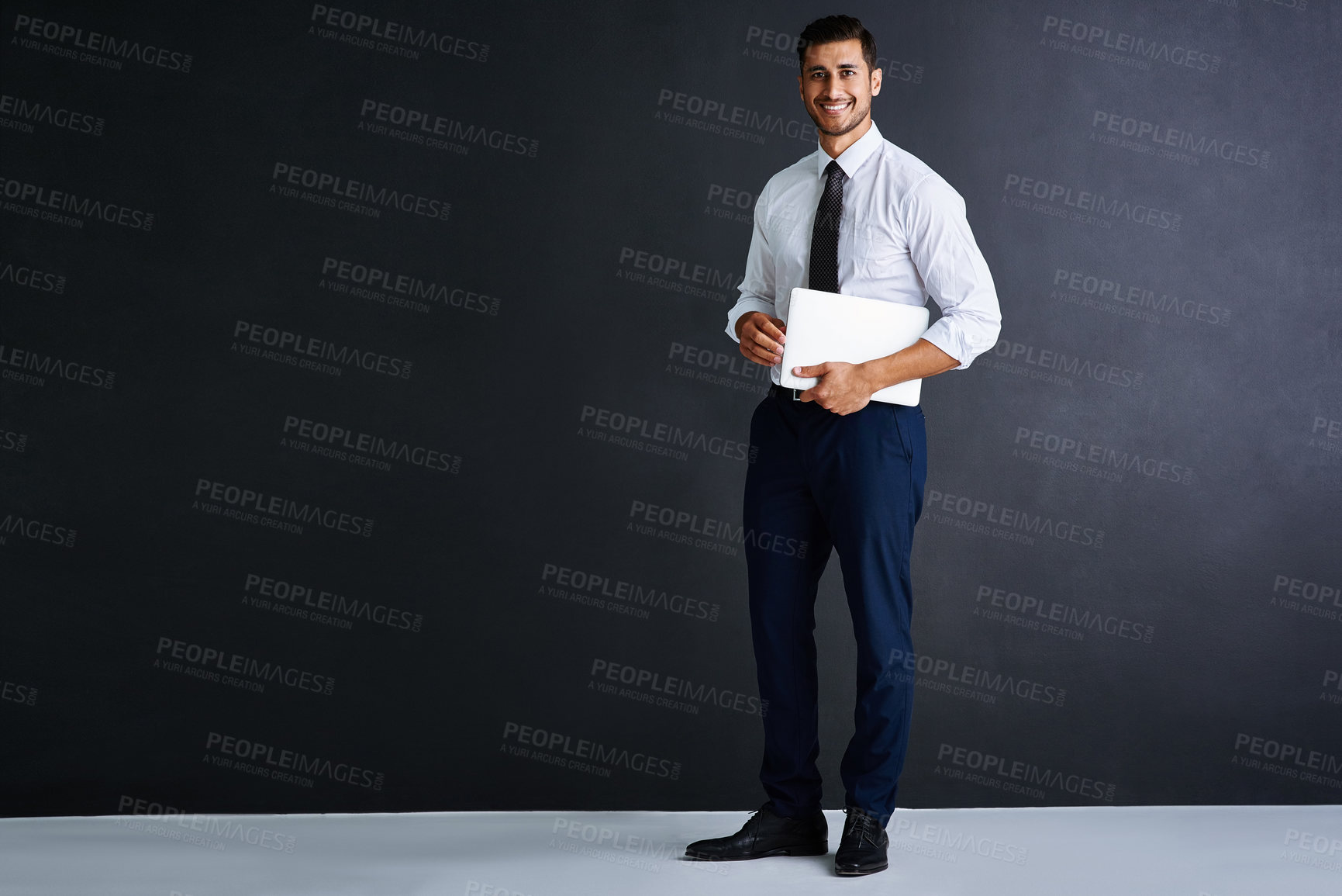 Buy stock photo Studio portrait of a young businessman standing against a black background
