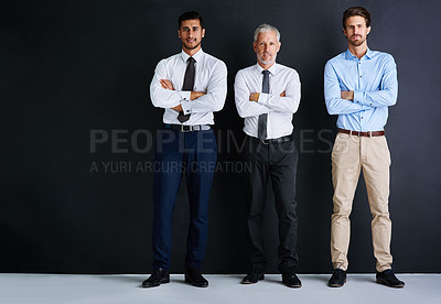 Buy stock photo Studio portrait of three businessman standing against a black background