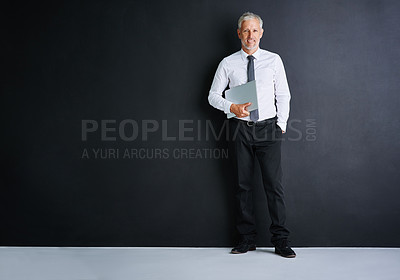Buy stock photo Studio portrait of a mature businessman standing against a black background