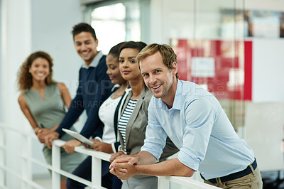 Buy stock photo Portrait of a group of smiling coworkers leaning on a railing in an office