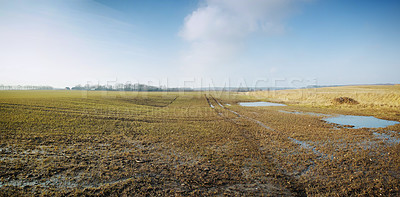 Buy stock photo Wet farmland in early spring in Jutland, Denmark. Grassland with puddles of water against cloudy blue sky. Agriculture field destroyed by water erosion damage on crop or grain in farmland after rain