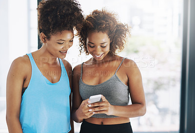Buy stock photo Cropped shot of two young women looking at a cellphone after yoga class