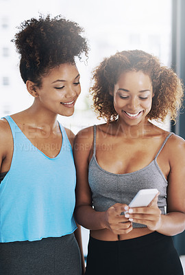 Buy stock photo Cropped shot of two young women looking at a cellphone after yoga class