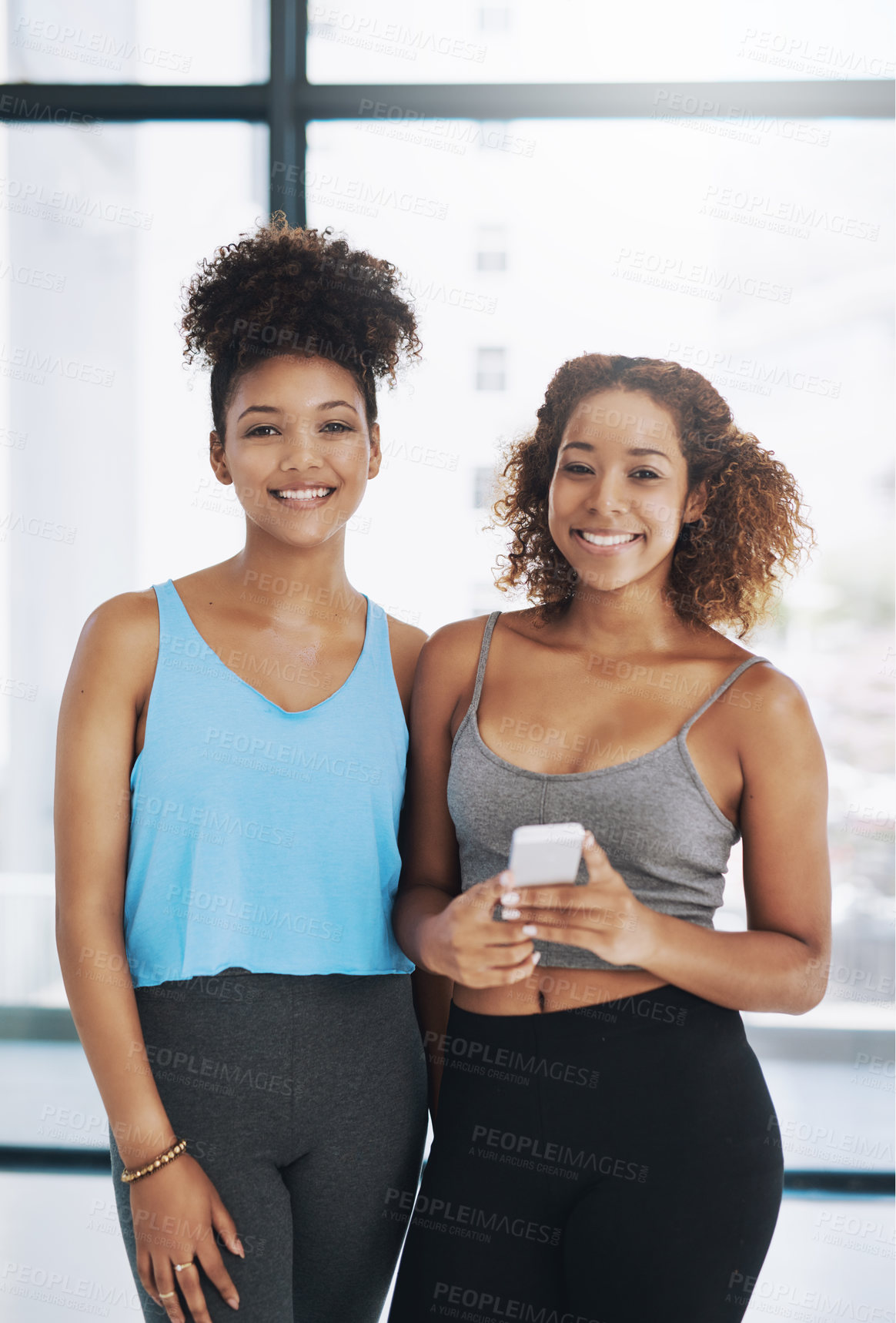 Buy stock photo Cropped portrait of two young women looking at a cellphone after yoga class