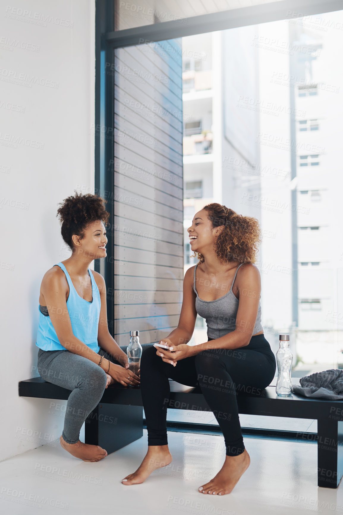 Buy stock photo Laughing, phone and women on yoga class break for support, wellness or share health advice. Relax, mobile app or friends on floor talking in discussion or gossip together for news, resting or pilates