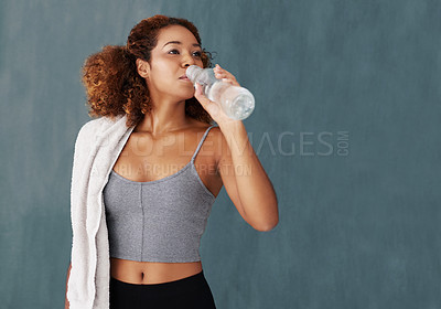 Buy stock photo Studio shot of a young woman drinking some water after yoga class against a grey background