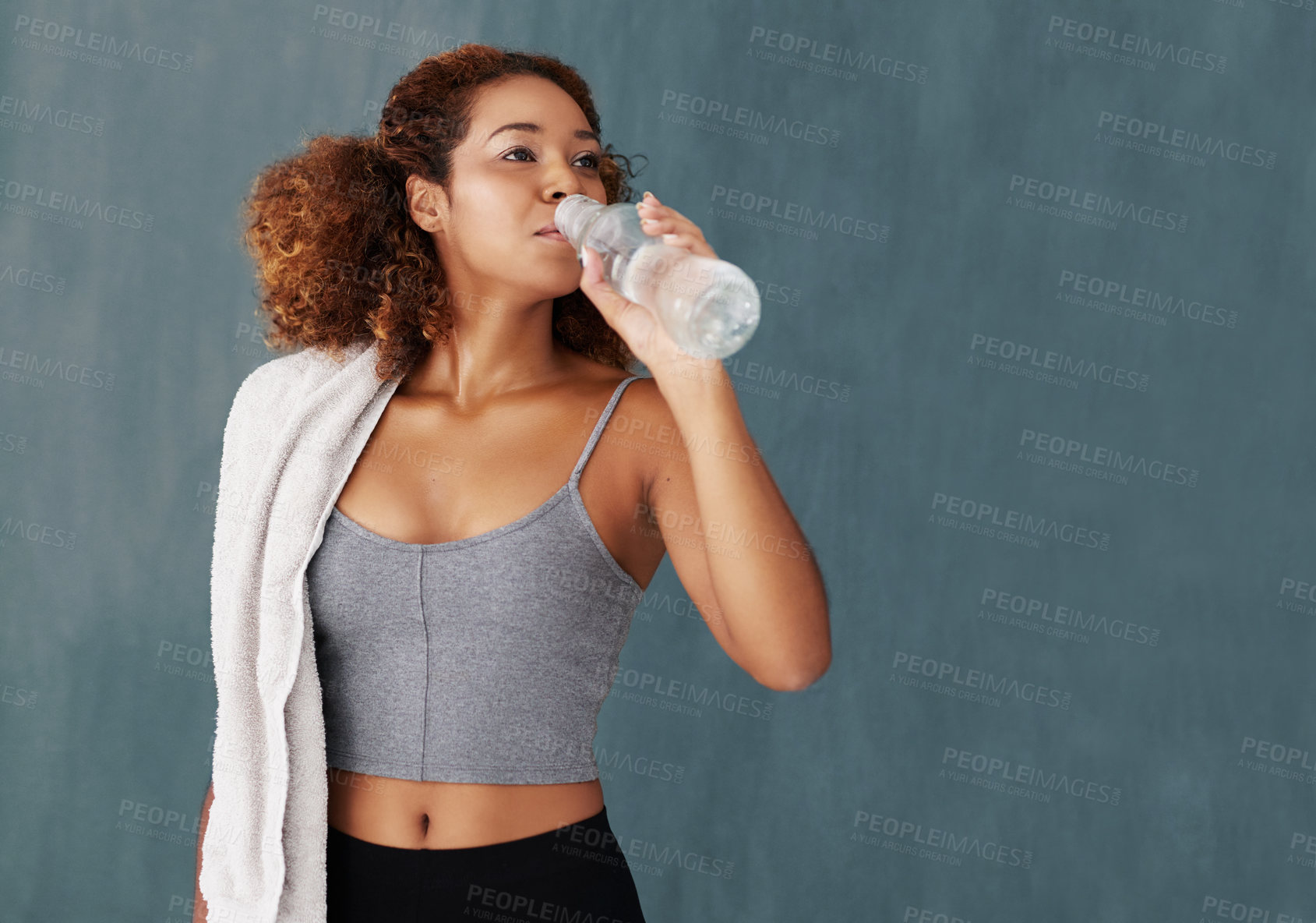 Buy stock photo Studio shot of a young woman drinking some water after yoga class against a grey background