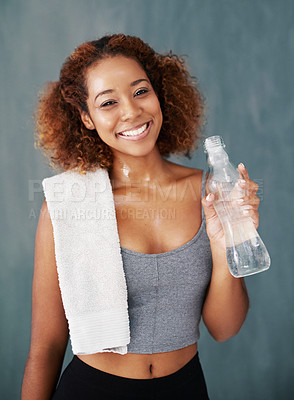 Buy stock photo Studio portrait of a young woman drinking some water after yoga class against a grey background