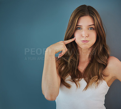 Buy stock photo Studio portrait of an attractive young woman touching her cheek against a gray background