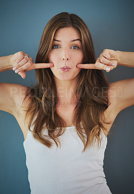Buy stock photo Studio portrait of an attractive young woman playfully poking her cheeks against a gray background