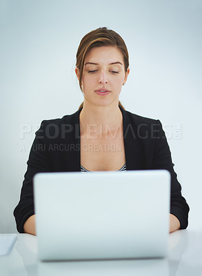 Buy stock photo Studio shot of a young businesswoman working on her laptop