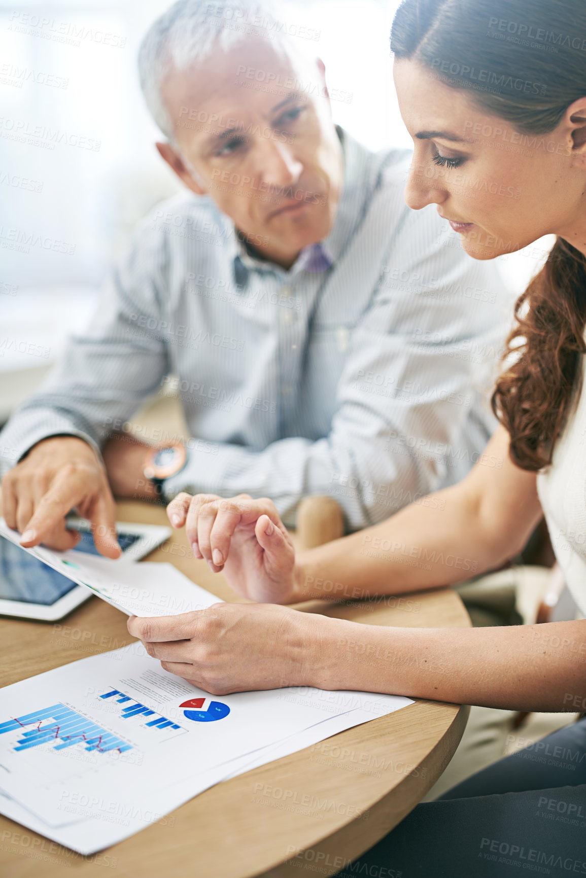 Buy stock photo Shot of two coworkers sitting at a table discussing paperwork