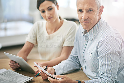 Buy stock photo Portrait of two coworkers sitting at a table discussing paperwork