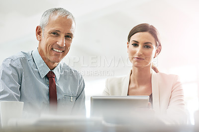 Buy stock photo Portrait of two coworkers sitting at a table using a digital tablet