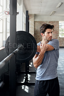 Buy stock photo Shot of a young man stretching before working out in the gym