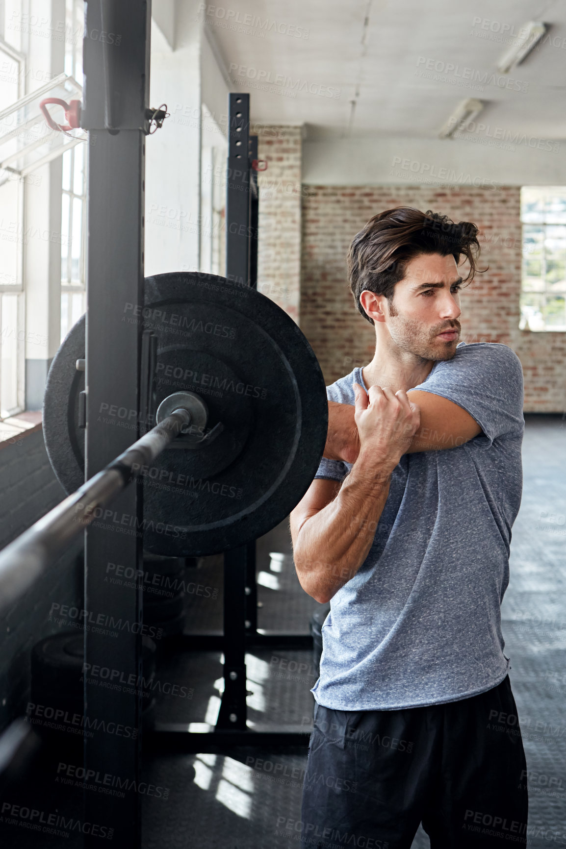 Buy stock photo Shot of a young man stretching before working out in the gym