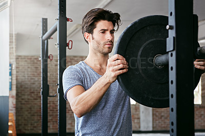 Buy stock photo Shot of a young man about to work out with weights in the gym