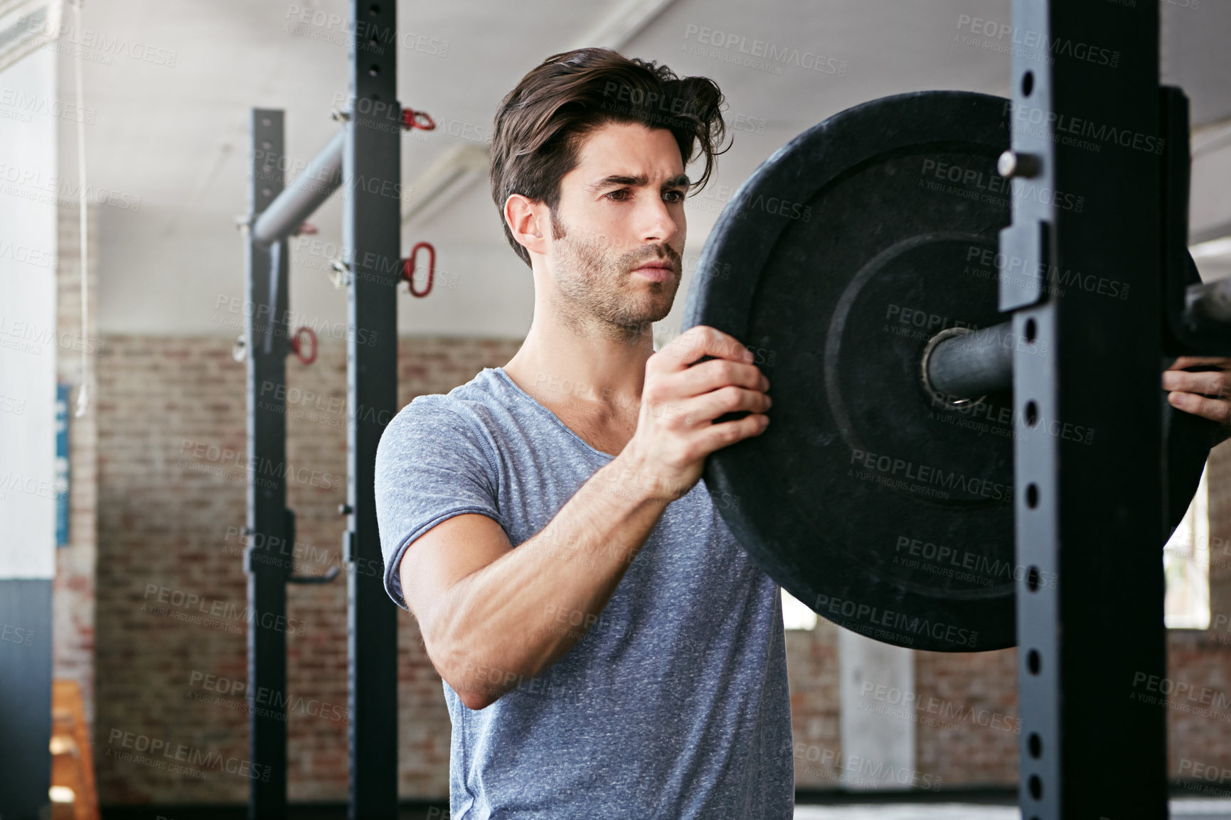 Buy stock photo Shot of a young man about to work out with weights in the gym