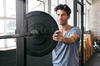 Buy stock photo Shot of a young man about to work out with weights in the gym