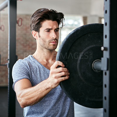 Buy stock photo Shot of a young man about to work out with weights in the gym