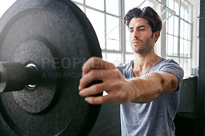 Buy stock photo Shot of a young man about to work out with weights in the gym