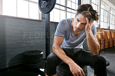 Buy stock photo Shot of a young athlete looking tired after working out in the gym
